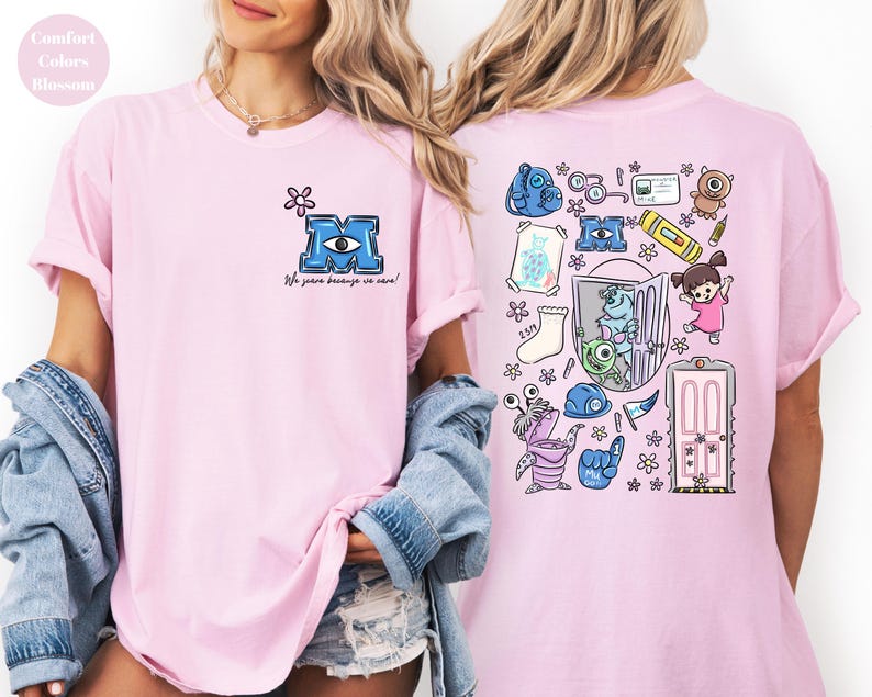 May include: Light pink t-shirt featuring a blue letter "M" with an eye design and the phrase "We scare because we care!" on the front. The back of the shirt has a colorful cartoon graphic with various characters and objects.