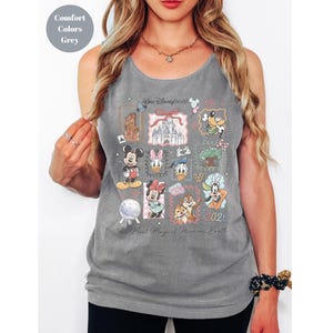 May include: Gray tank top featuring a collage of Disney characters and landmarks. The design includes Mickey Mouse, Minnie Mouse, Donald Duck, and Chip and Dale, with the text "Walt Disney World" and "2026". The phrase "The Most Magical Place on Earth" is also visible.
