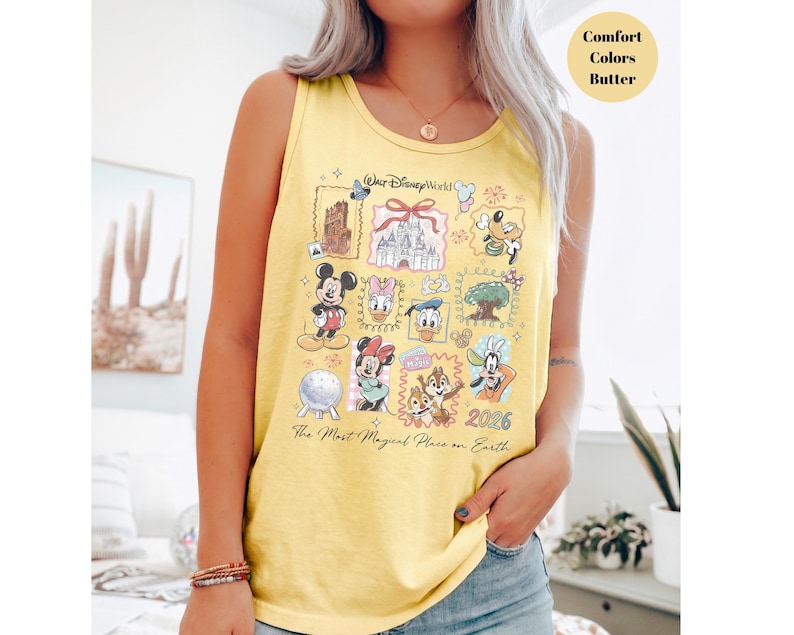 May include: Yellow tank top with a colorful Disney World graphic. The graphic features various Disney characters and landmarks, with the text "Walt Disney World" and "The Most Magical Place on Earth". The year "2026" is also displayed.