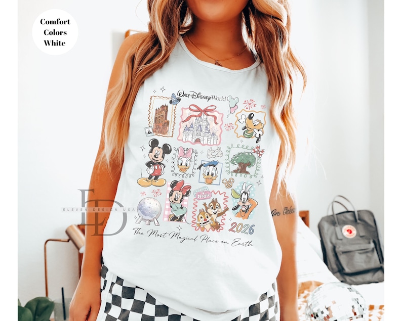 May include: White tank top featuring a colorful Disney World graphic. The design includes various Disney characters and landmarks, with the text "Walt Disney World" and "The Most Magical Place on Earth". The year "2026" is also displayed.