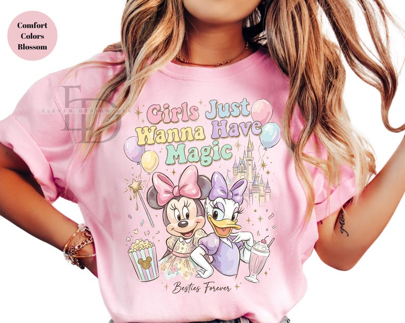 Puede incluir: Camiseta rosa claro con Minnie Mouse y Daisy Duck y el texto "Girls Just Wanna Have Magic". El dise&ntilde;o incluye un castillo, globos, palomitas de ma&iacute;z y un batido. Tambi&eacute;n se incluyen las palabras "Besties Forever".