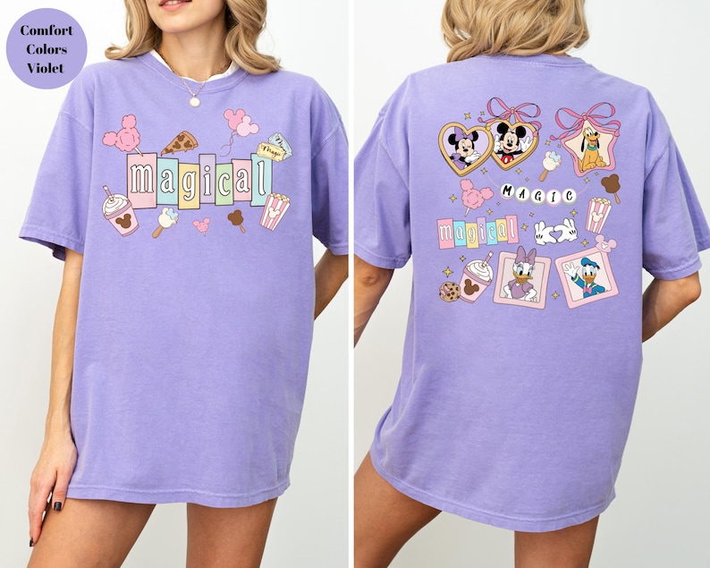 Op de afbeelding: Een lila T-shirt met het woord "magical" in kleurrijke blokletters op de voorkant. Het shirt heeft cartoonafbeeldingen van Mickey Mouse, Minnie Mouse en andere Disney-personages. De achterkant van het shirt heeft het woord "magic" en meer Disney-personageafbeeldingen.