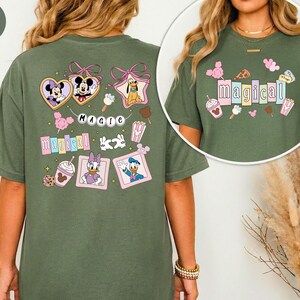 Op de afbeelding: Een mosgroen t-shirt met kleurrijke Disney-personageafbeeldingen. Het shirt bevat afbeeldingen van Mickey en Minnie Mouse, Pluto, Daisy en Donald Duck, en het woord "magical". Het shirt heeft een comfortabele, oversized pasvorm.
