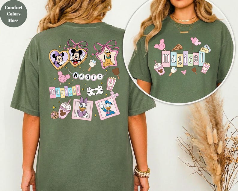 Op de afbeelding: Een mosgroen t-shirt met kleurrijke Disney-personageafbeeldingen. Het shirt bevat afbeeldingen van Mickey en Minnie Mouse, Pluto, Daisy en Donald Duck, en het woord "magical". Het shirt heeft een comfortabele, oversized pasvorm.