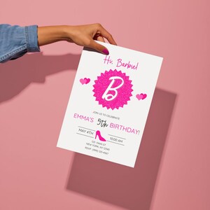 May include: A white invitation card with pink text and graphics, held against a pink background. The card reads "Hu. Barbiel" and "Emma's 5th Birthday!" with a pink high heel graphic. The invitation includes date, time, and location details.