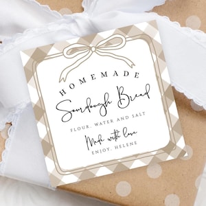May include: A white gift tag with a brown and white gingham pattern. The tag has a brown bow and the text "HOMEMADE Sourdough Bread FLOUR, WATER AND SALT Make with love ENJOY. HELENE"