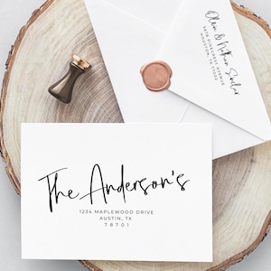 May include: A white invitation card with the text "The Anderson's" and address details. An envelope with a wax seal and the names "Olivia & Nathan Sinclair" is also present. A gold-colored wax stamp is on a wooden surface.
