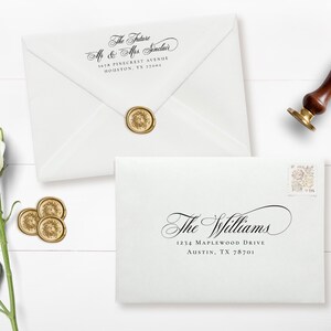 May include: White envelopes with elegant calligraphy, sealed with gold wax stamps. One envelope reads "The Future Mr & Mrs Sinclair" and the other reads "The Williams". A wooden handled wax stamp and white roses are also present.