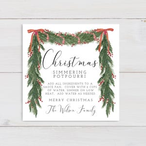 Könnte beinhalten: Eine quadratische Weihnachtskarte mit einem dekorativen Girlanden-Design. Die Girlande ist grün mit roten Beeren und Schleifen. Die Karte enthält den Text "Christmas Simmering Potpourri" und Anweisungen.