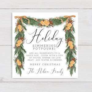 May include: A white card featuring the words "Holiday Simmering Potpourri" in cursive, decorated with a garland of fir, dried orange slices, and berries. Includes instructions and the phrase "Merry Christmas".