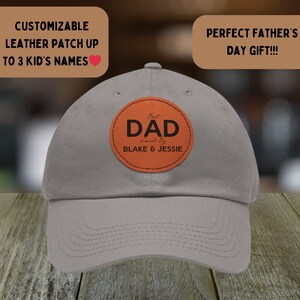 Può includere: Un cappello da baseball grigio con una toppa in pelle marrone che dice "Best Dad Loved By Blake & Jessie".