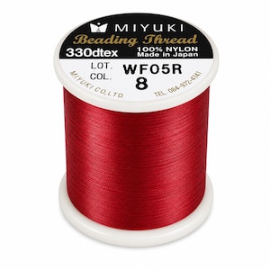 May include: A spool of red Miyuki beading thread made of 100% nylon. The white label on top reads MIYUKI Beading Thread, 330dtex, Made in Japan, LOT. WF05R, COL. 8, and includes the company name and phone number. The thread is wound tightly around the spool.
