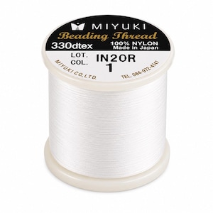Może przedstawiać: Szpula białej nici do koralików Miyuki wykonanej w 100% z nylonu. Etykieta zawiera tekst MIYUKI Beading Thread, 330dtex, 100% NYLON, Made in Japan, LOT. IN20R, COL. 1, MIYUKI CO., LTD. oraz numer telefonu 084-972-4141.