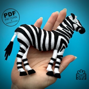 May include: A black and white zebra plush toy with a PDF pattern and instructions for making it. The toy is being held in a person's hand.