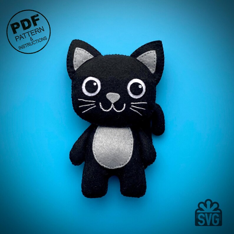 May include: A black felt cat plushie with gray accents on the ears, chest, and nose. The cat has large white eyes, white whiskers, and a stitched smile. The image includes text that says "PDF PATTERN & INSTRUCTIONS" and "SVG".