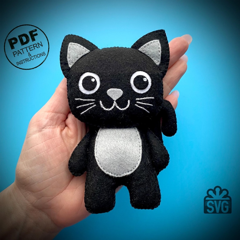 May include: A handmade black felt cat plushie with gray accents. The cat has large white eyes, white whiskers, and a gray nose and belly. The image includes the text "PDF PATTERN & INSTRUCTIONS" in a circle.