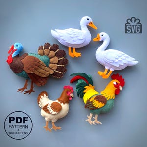 Puede incluir: Un conjunto de cinco adornos de fieltro que incluyen un pavo, dos gansos, una gallina y un gallo. El pavo tiene detalles en marrón, verde azulado y rojo. Los gansos son blancos con patas naranjas. La gallina es crema y marrón, y el gallo es amarillo, verde y rojo. Incluye etiquetas de texto SVG y PDF.