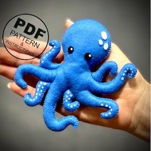 May include: A blue felt octopus with white spots and black eyes. The octopus has eight tentacles and is a handmade toy. The image includes the text "PDF PATTERN & INSTRUCTIONS".
