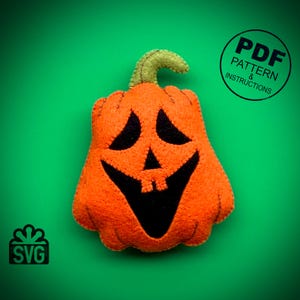 May include: A felt orange pumpkin with a black smiling face. The pumpkin has a green stem. The image includes the text "PDF PATTERN & INSTRUCTIONS" and "SVG".