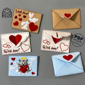 May include: A collection of handmade felt envelope designs. The envelopes feature red hearts, stitched details, and the phrase "With love!" Some designs include a cat, rabbits, and clouds. The color palette includes beige, white, and blue.