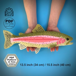 Puede incluir: Un peluche de trucha arcoíris hecho de fieltro con cuerpo color canela, puntos negros, una franja lateral rosa y detalles en las aletas. El producto incluye patrones SVG y PDF con instrucciones para dos tamaños: 34 cm y 40 cm.