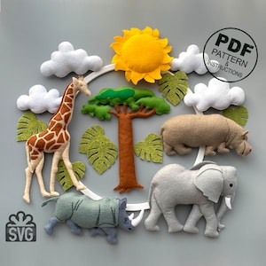 May include: A felt mobile featuring a giraffe, rhino, elephant, hippopotamus, and a tree. The mobile also includes a sun, clouds, and leaves. The mobile is suspended from a white hoop. The text "PDF PATTERN & INSTRUCTIONS" is on a white tag. The text "SVG" is on a white gift box.