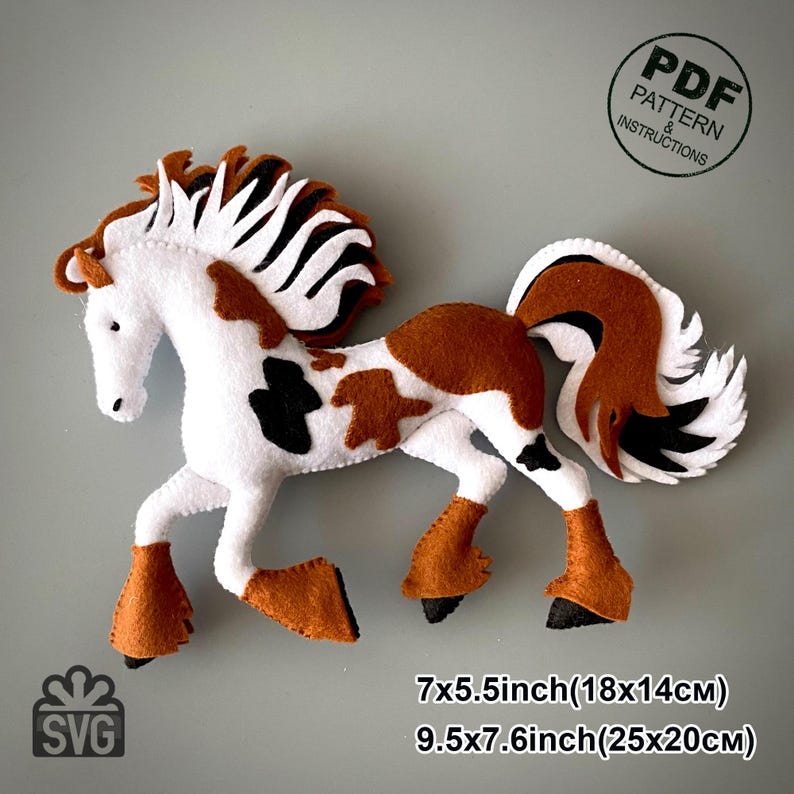May include: A felt horse in white, brown, and black. The horse has a flowing mane and tail, with brown hooves and markings. The image includes the text "PDF Pattern & Instructions" and "SVG", and measurements of 7x5.5 inches (18x14cm) and 9.5x7.6 inches (25x20cm).