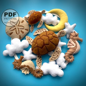 May include: A felt mobile with a brown and white sea turtle, a yellow crescent moon, a white sand dollar, a brown and white seahorse, and white clouds. The mobile is made of felt and is perfect for a nursery or child's room.