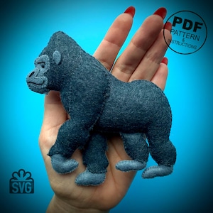 May include: A handmade, dark gray felt gorilla toy with light gray facial features and feet. The gorilla is in a walking pose. The image includes the text "PDF PATTERN & INSTRUCTIONS" and an SVG logo.
