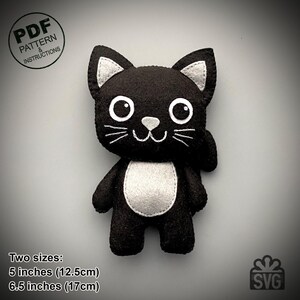 May include: A black felt cat plushie with white accents on the ears, chest, and face. The cat has large white eyes and embroidered whiskers. The plushie is available in two sizes: 5 inches (12.5cm) and 6.5 inches (17cm). The image includes the text "PDF PATTERN & INSTRUCTIONS".