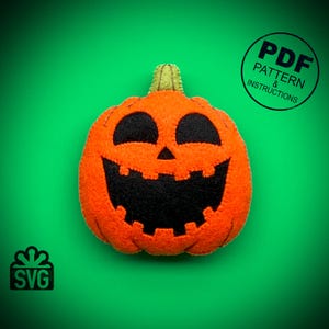 May include: A felt orange pumpkin with a black smiling face. The pumpkin is on a green background. The text "PDF PATTERN & INSTRUCTIONS" is in a black circle on the right side of the image. The text "SVG" is in a white box with a green bow on the left side of the image.