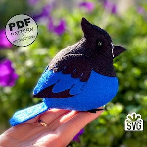 Peut inclure: Un oiseau bleu jay en feutre avec des ailes noires et une tête noire. L'oiseau est assis sur une main. L'image comprend le texte "PDF PATTERN & INSTRUCTIONS" et "SVG".