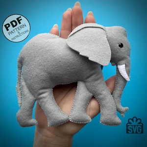 Op de afbeelding: Een grijs vilten olifantenspeelgoed met witte slagtanden en zwarte ogen. De olifant wordt in een hand gehouden tegen een blauwe achtergrond. De afbeelding bevat de tekst "PDF Pattern & Instructions".
