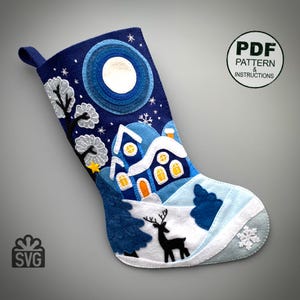 Peut inclure: Une chaussette de Noël en feutre bleu marine avec une scène d'hiver. Le motif comprend une pleine lune, des maisons enneigées, des arbres et un cerf. Le texte "PDF PATTERN & INSTRUCTIONS" est dans un cercle à droite.