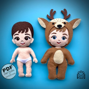Puede incluir: Dos muñecas de fieltro, una vestida de reno y la otra con un pañal. La muñeca reno tiene cuernos marrones, un cuerpo marrón y una cara de color crema. La otra muñeca tiene cabello marrón, una cara de color crema y un pañal blanco. Ambas muñecas tienen detalles cosidos y están hechas a mano.