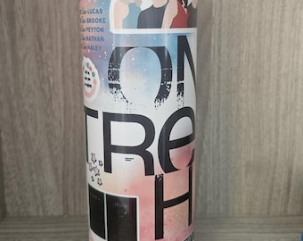 May include: A stainless steel tumbler with a colorful design featuring the text "One Tree Hill" in large black letters. The tumbler includes images of characters and names from the show, with a watercolor-style background.