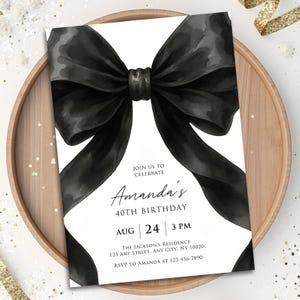 Może przedstawiać: Białe zaproszenie z dużym czarnym łukiem akwarelowym. Karta ogłasza 40. urodziny Amandy, w tym datę, godzinę i miejsce. Zaproszenie jest prezentowane na drewnianej tacy.
