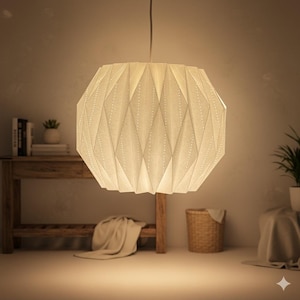 May include: A hanging, off-white geometric pendant light. The lamp has a faceted design with small, evenly spaced perforations. The light fixture is suspended from a thin, gray cord and illuminates a warm, inviting space. The lamp's shape is reminiscent of a paper lantern.