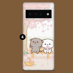 Puede incluir: Una funda para tel&eacute;fono con un fondo rosa y blanco que presenta dos gatos de dibujos animados sentados en un banco bajo un cerezo en flor. Los gatos sostienen una bebida y una cesta de flores. La funda tiene una parte posterior transparente y un recorte de c&aacute;mara negro.