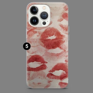 May include: A clear phone case with a red and white pattern of lipstick kisses. The case is designed for an iPhone.