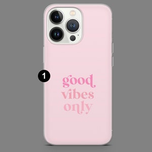May include: A pink phone case with a clear back and a white camera bump. The case has the text "good vibes only" printed in pink.