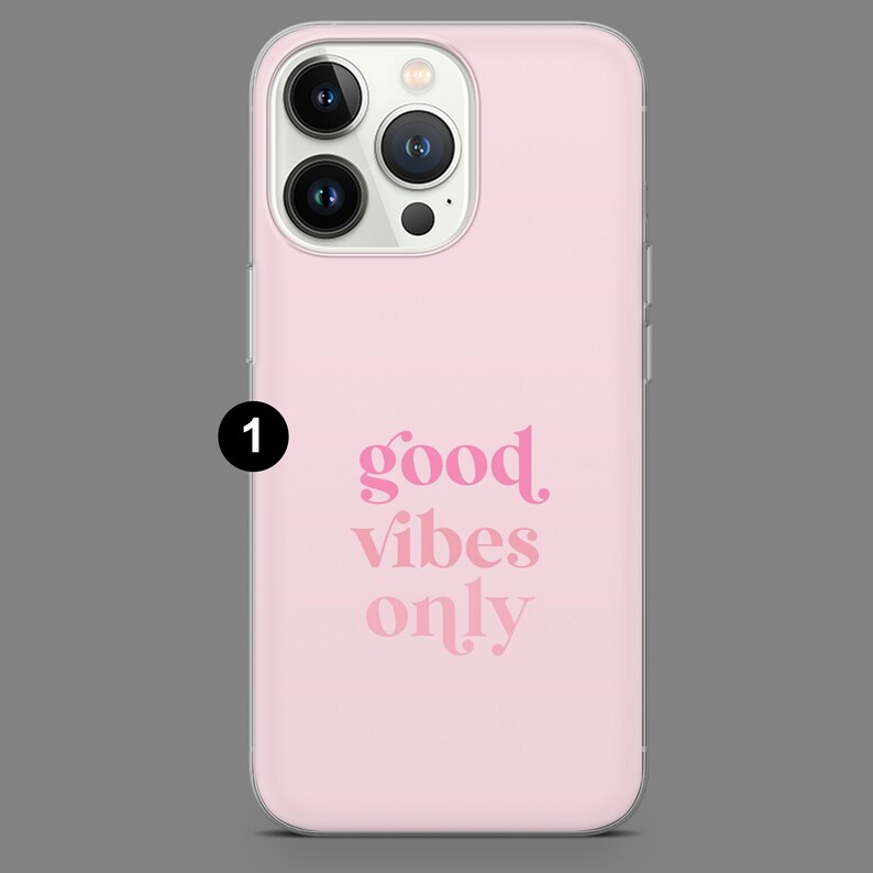 May include: A pink phone case with a clear back and a white camera bump. The case has the text "good vibes only" printed in pink.