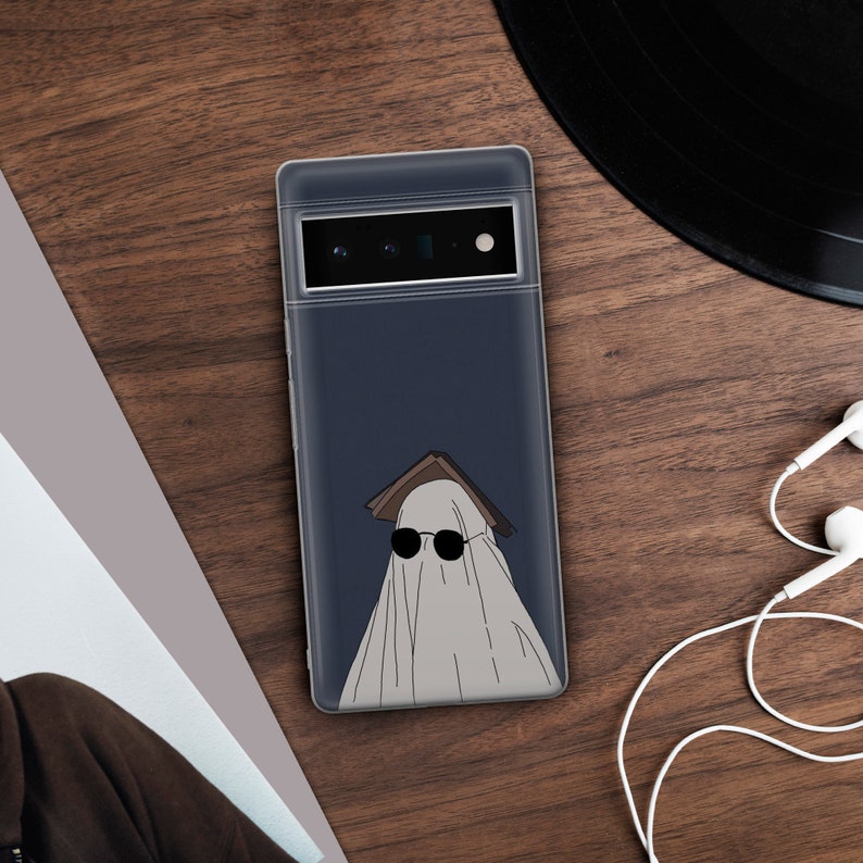 May include: A clear phone case with a dark blue background and a white ghost wearing sunglasses and a book on its head.