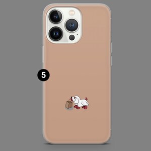 Puede incluir: Una funda de tel&eacute;fono transparente con un fondo de color melocot&oacute;n. Una ilustraci&oacute;n de dibujos animados de un perro con un disfraz de fantasma blanco y sosteniendo una bolsa de papel marr&oacute;n est&aacute; en la funda.