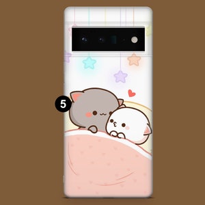 Puede incluir: Una funda de tel&eacute;fono blanca y gris con una linda ilustraci&oacute;n de dibujos animados de dos gatos acurrucados bajo una manta rosa. El fondo es azul claro con estrellas blancas.