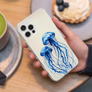 May include: A clear phone case with a watercolor design of two blue jellyfish on a white background.