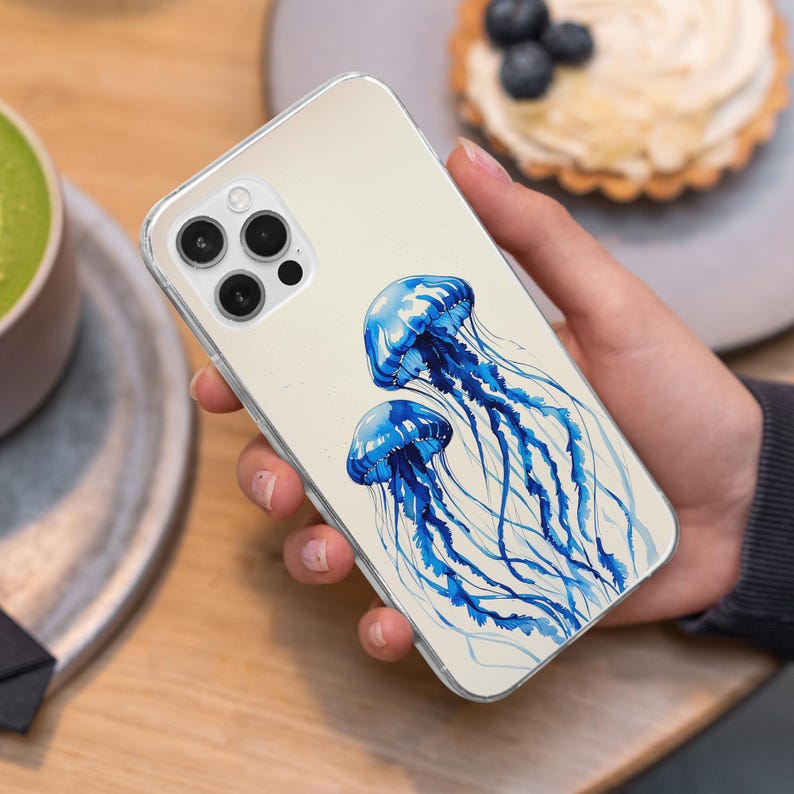 May include: A clear phone case with a watercolor design of two blue jellyfish on a white background.