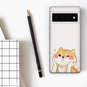 Puede incluir: Carcasa de tel&eacute;fono blanca con un perro Shiba Inu de dibujos animados con una expresi&oacute;n feliz. El perro es marr&oacute;n claro con mejillas rosadas y se est&aacute; sosteniendo las patas frente a la cara.