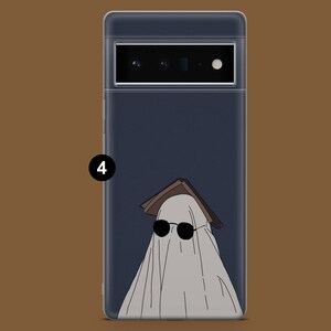 May include: A phone case with a dark blue background and a white ghost wearing sunglasses and a book on its head.