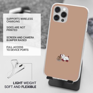 Puede incluir: Una funda transparente para tel&eacute;fono con un fondo marr&oacute;n claro y un perro de dibujos animados blanco que lleva una bolsa de papel marr&oacute;n. La funda est&aacute; dise&ntilde;ada para admitir la carga inal&aacute;mbrica y tiene un parachoques elevado para proteger la pantalla y la c&aacute;mara.